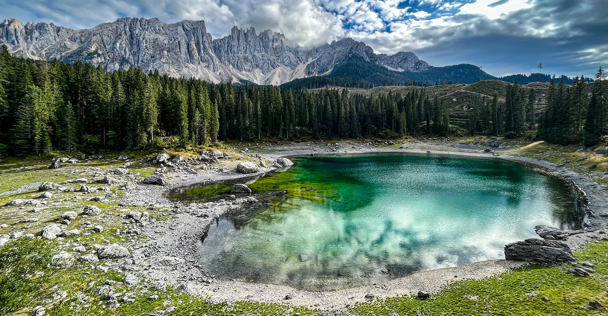 View of the turquoise Lake Karersee (Lago di Carezza) with the mountain massif in the background, Dolomites, Italy.