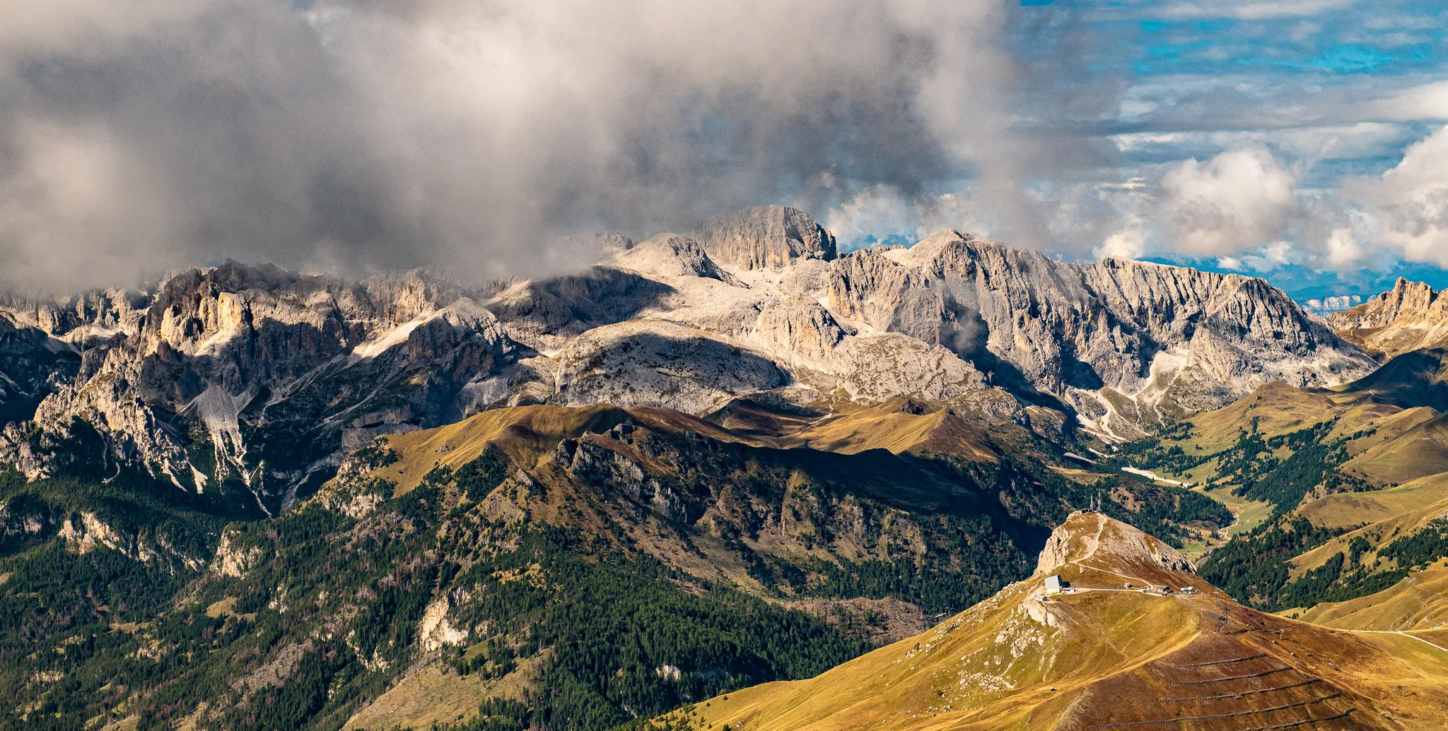 Sass Pordoi mountain peak and Sella massif on a cloudy sunny afternoon, Dolomites, Italy.